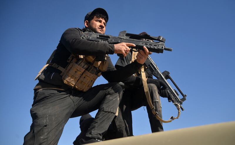 Members of the Iraqi forces and the Hashed Al Shaabi carry their firearms as they stand on an infanty-fighting vehicle near the Iraqi-Syrian border, about 80km west of the border town of al-Qaim, on December 9, 2017.