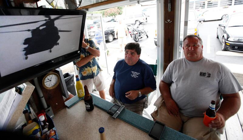 Virginia Beach residents Tom Hall, left, and Mark Janik, center, watch as news about the Navy Seal Team Six helicopter accident is displayed on a television at a bar in Virginia Beach , Va., Saturday, Aug. 6, 2011. The headquarters for the Navy Seal Team Six is located in Virgina Beach. (AP Photo/Steve Helber) *** Local Caption ***  Afghanistan Seals Virginia.JPEG-02ce8.jpg