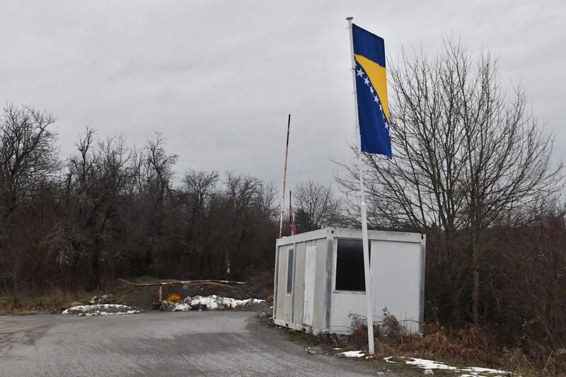 This picture taken on January 30, 2021, shows police containers at blocked-off crossing on Bosnia - Croatia border in the northern-bosnian village of Bosanska Bojna. Bosanska Bojna is mostly unpopulated village, with war damaged houses and homesteads, abandoned by their Bosnian-Serb owners, after Bosnia's 1992-95 war, near town of Velika Kladusa, in Northern Bosnia. In present times the village is frequented by illegal migrants from Asia, in their atempts to cross the border, on their way towards the Western-European countries. Due to police push-backs by Croatian border police, some migrant families inhabit abandoned houses in Bosanska Bojna, to remain closer to the border and prepare for further atempts to cross the closely guarded EU border. / AFP / ELVIS BARUKCIC
