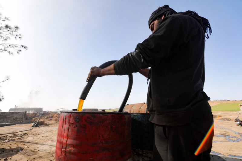 A worker fills a barrel with fuel produced at an amateur oil refinery near Tarhin, in Aleppo, Syria. AFP