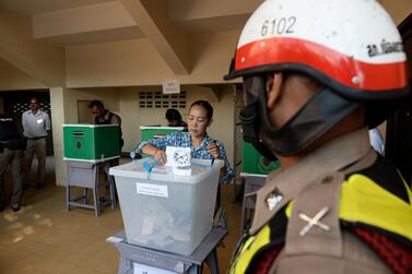 A policeman stands guard as a woman casts her ballot at a polling station in Narathiwat on March 24, 2019, during Thailand's general election. AFP 