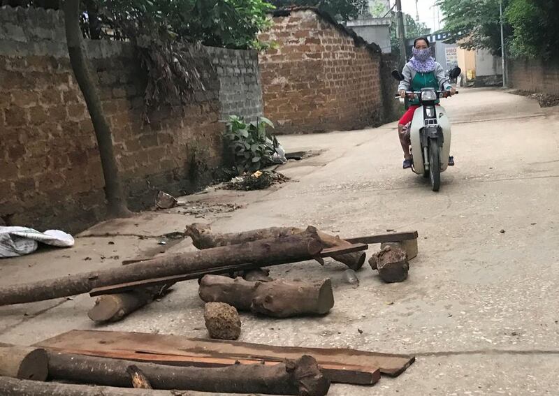 A woman riding a motorcycle along an alley with loose rocks and logs placed by villagers in My Duc district on the outskirts of Hanoi on April 20, 2017.  A group of Vietnamese farmers who took more than a dozen police and officials hostage over a land dispute have sealed off their village. AFP 