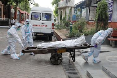 Health workers use a handcart, usually used for transporting goods, to carry the body of a Covid-19 victim into a crematorium in New Delhi, India on June 28, 2020. Reuters