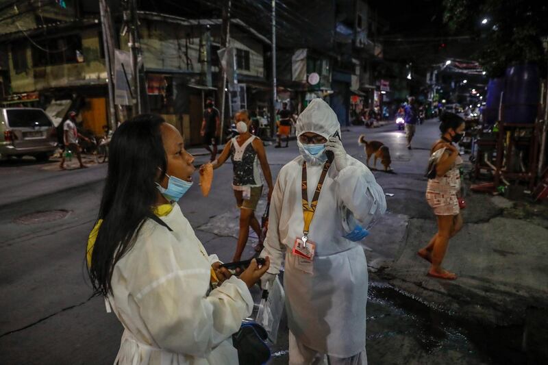 Health workers Mercelina Villacampa (L) and Richell Arsenio wait for Vannessa Morales before their night rounds in Manila, Philippines.  They are part of a group of four volunteer health workers who were nicknamed 'Astronauts' by residents of Village 775, Zone 84 in Manila as they resemble such when donning their protective equipment. The healthcare volunteers conduct home visits twice a day to people infected or suspected to be infected with the novel SARS-CoV-2 coronavirus that causes the COVID-19 disease in one of the densely populated villages in Manila.  EPA
