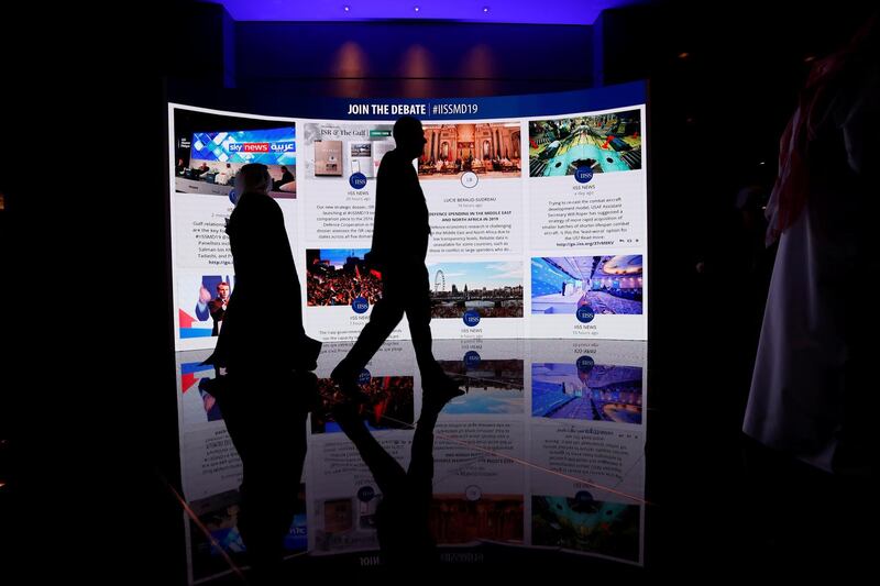 Visitors pass in front of an advertisement screen at the 15th Regional Security Summit IISS Manama Dialogue 2019. REUTERS