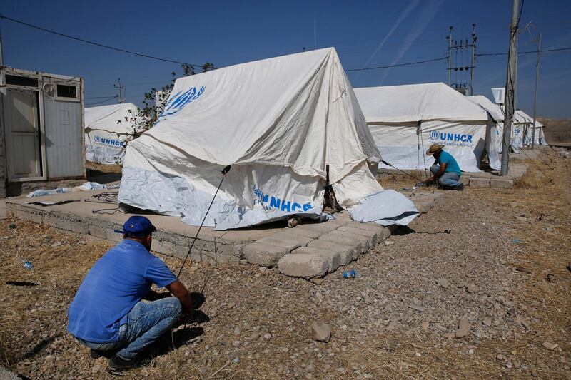 Workers set tents in preparation to receive a few hundred Syrian refugees who have been newly displaced by the Turkish military operation in northeastern Syria, at the Bardarash camp, north of Mosul, Iraq, Wednesday, Oct. 16, 2019. The camp used to host Iraqis displaced from Mosul during the fight against the Islamic State group and was closed two years ago. The U.N. says more around 160,000 Syrians have been displaced since the Turkish operation started last week, most of them internally in Syria. (AP Photo/Hussein Malla)
