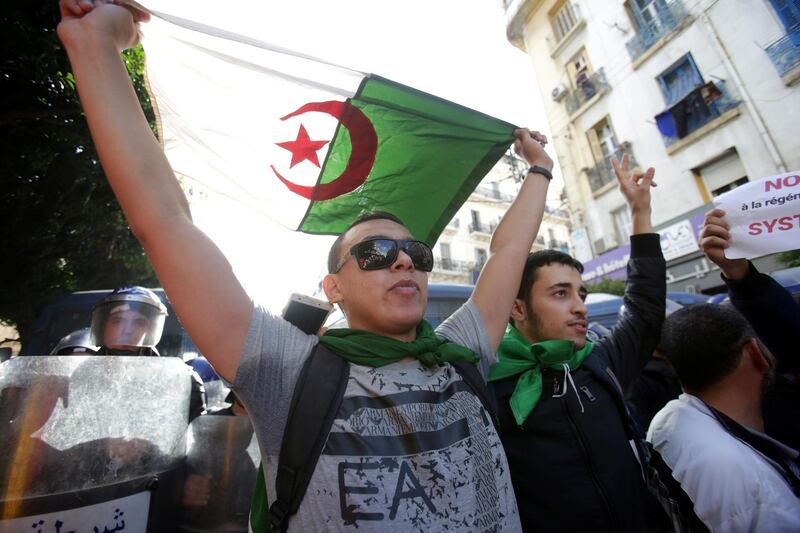 A demonstrator with flag gestures near police officers standing guard during a protest against the country's ruling elite and rejecting the presidential election in Algiers, Algeria. REUTERS