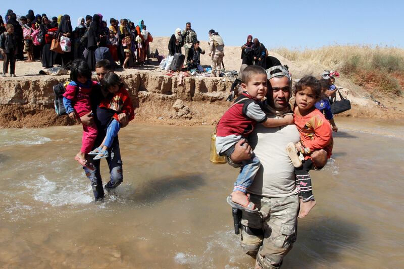 A member of Kurdish Peshmerga forces (R) helps people, who fled from their homes in Hawija, as they arrive to be transported to camps for displaced people, in southwest of Kirkuk, Iraq October 4, 2017. REUTERS/Ako Rasheed