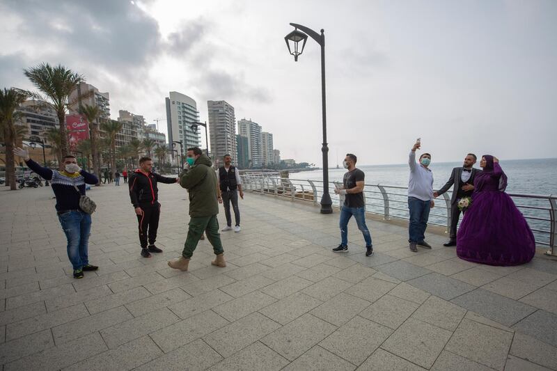 A bride and groom, right, take a selfie as Municipal policemen order them to evacuate the corniche, or waterfront promenade in Beirut. AP Photo