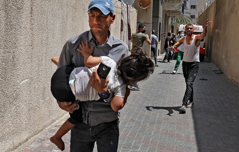 A man carries a child as Palestinians evacuate a building targeted by an Israeli bombardment in Gaza City. AFP
