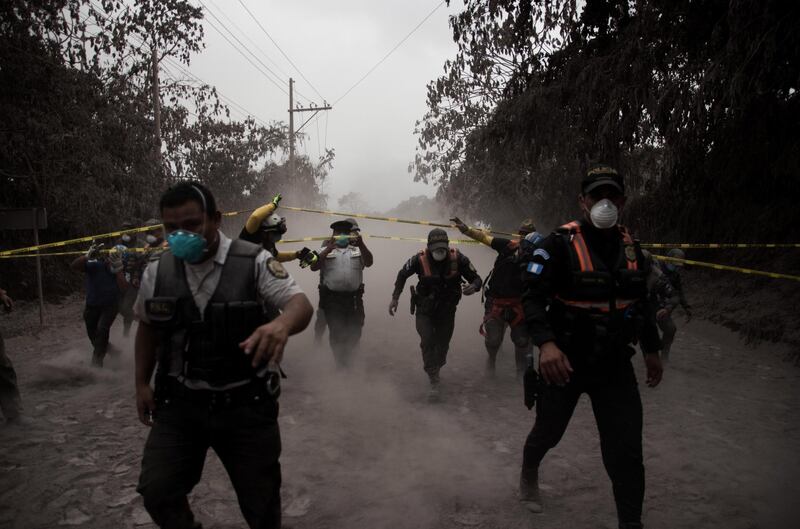 Guatemalan policemen help people evacuate in the village El Porvenir, Guatemala after the eruption of the Fuego volcano, which has left at least seven people dead, around 20 injured and 1.7 million people affected, according to the Guatemalan authorities. Jose Misa / EPA