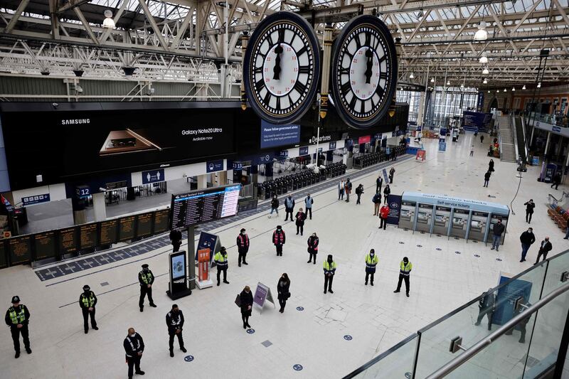 Commuters take part in a minute's silence on the first anniversary of the first national Covid-19 lockdown, at Waterloo Station in central London. AFP