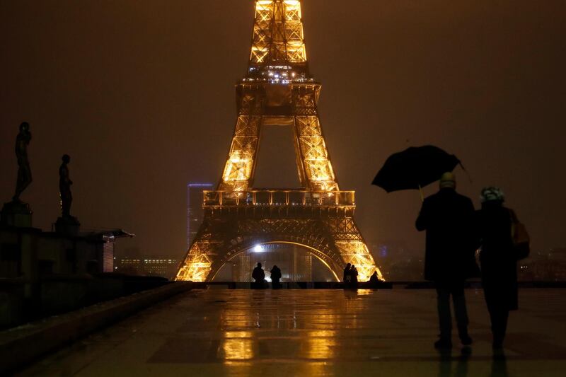 A couple walk on the Trocadero square near the Eiffel Tower during the curfew in Paris. All of France is under a stricter curfew, which started on Saturday at 6pm and will last for at least 15 days. AP Photo