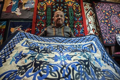 An Egyptian craftsman showcases a tapestry in his shop in Khayamiya Street, or the Street of Tent-makers, in the old city of the Egyptian capital Cairo on December 18, 2018. Along the sides of the roofed street of Khayamiya, or the Street of Tent-makers, dozens of craftsmen's shops have drawn foreign visitors for years until the 2011 uprising toppled longtime ruler Hosni Mubarak after which business has slowed to a trickle. The centuries-old art of Khayamiya, belived to have emerged during the Fatimid dynasty (10th-12th century AD), goes back to the time of travelling caravans, when huge tent pavilions were used as shields from the desert's searing sun. / AFP / Mohamed el-Shahed
