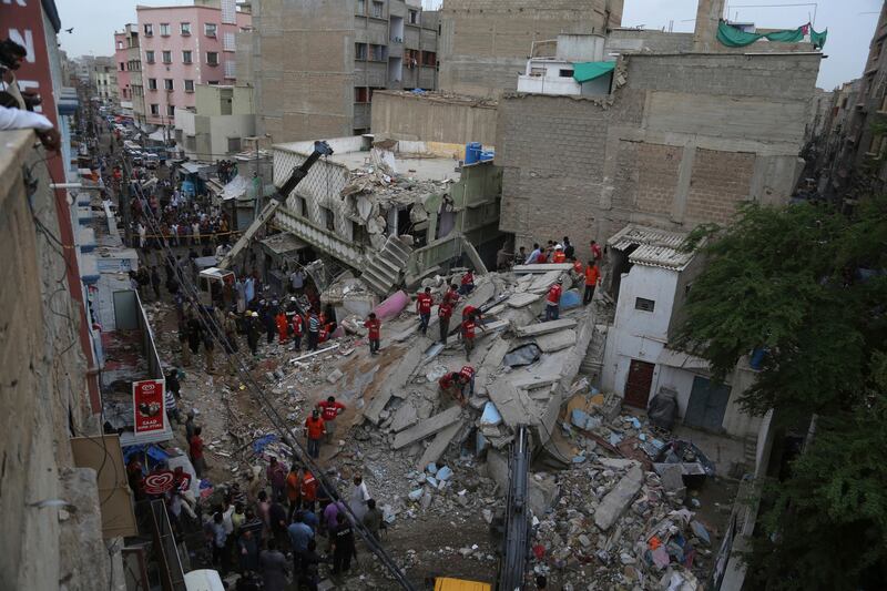 Volunteers look for trapped residents at the site of the building collapse. Shakil Adil / AP