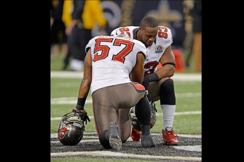 Tampa Bay Buccaneers players Adam Hayward, left, and defensive tackle Gerald McCoy, right, pause for a moment of silence in memory of 20 children and six adults killed Friday in a shooting rampage at Sandy Hook Elementary School in Newtown, Conn. Bill Feig / AP Photo