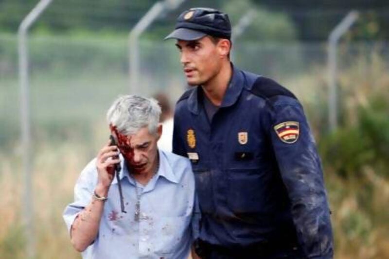 An injured man, identified by Spanish newspapers as the train driver Francisco Jose Garzon, is helped by a policeman after a train crashed near Santiago de Compostela, northwestern Spain.