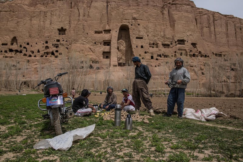 Potato farmers take a break from planting potatoes in Bamyan city; the remains of the Buddha statues in the background, blown up by the Taliban in 2001. 