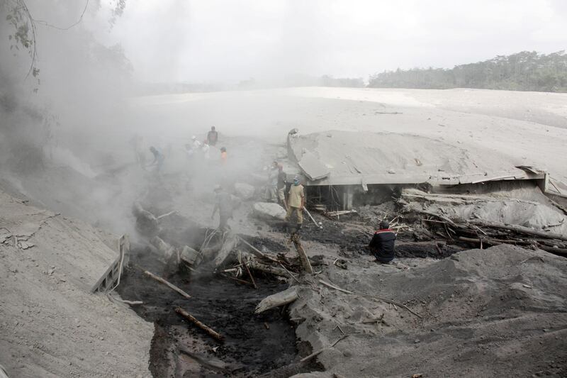 People are seen in a middle of a road blanketed with volcanic ash from the erupting Mount Semeru in Lumajang, East Java Province, Indonesia. Reuters