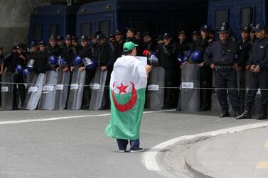 A protester wears the Algerian flag and carries a placard in front of police during a demonstration for the departure of the Algerian regime in Algiers, Algeria EPA