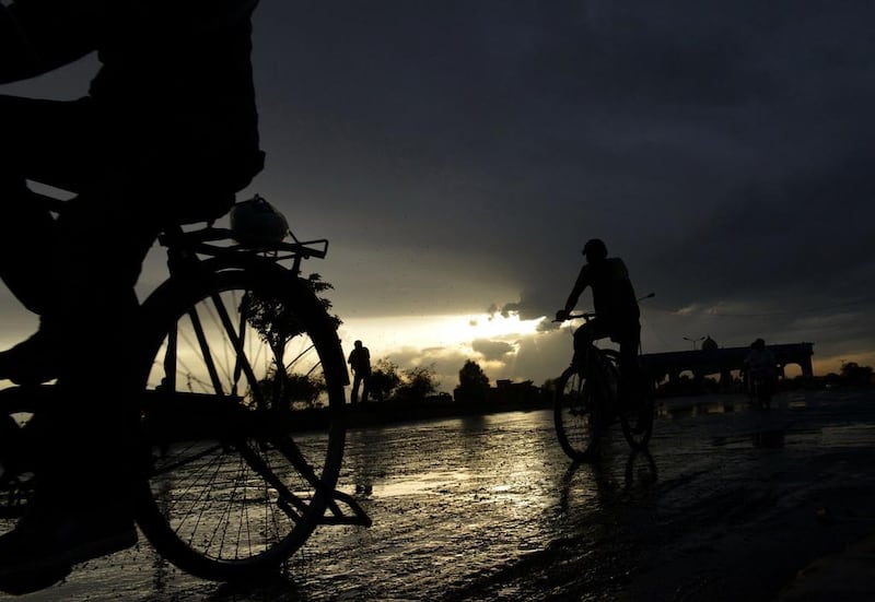 Pakistani men ride on their bicycles on a rainy day in Lahore, Pakistan. Arif Ali / AFP