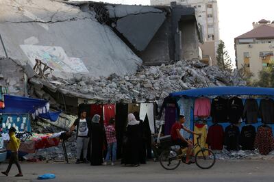 Women shop in the shadow of rubble of destroyed buildings hit by Israeli air strikes during an 11-day war between Gaza's Hamas rulers and Israel. AP