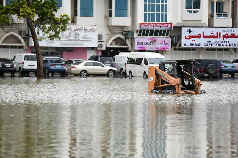 A construction vehicle partially submerged on a street in the city. Khushnum Bhandari / The National