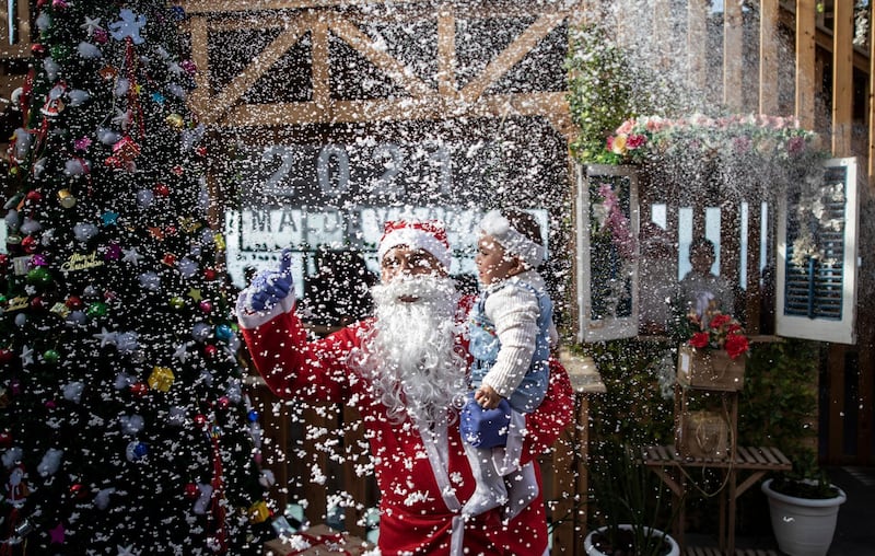 A Palestinian waiter dressed as Santa Claus holds a child for a photograph in a restaurant on the beach in Gaza City. AP