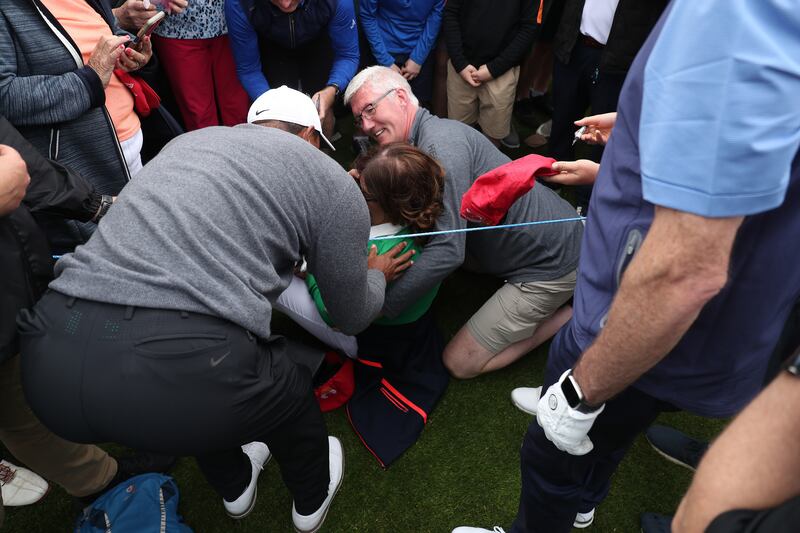 Tiger Woods speaks to a woman who was struck by the ball of British entrepreneur Peter Jones at the first hole. Getty Images