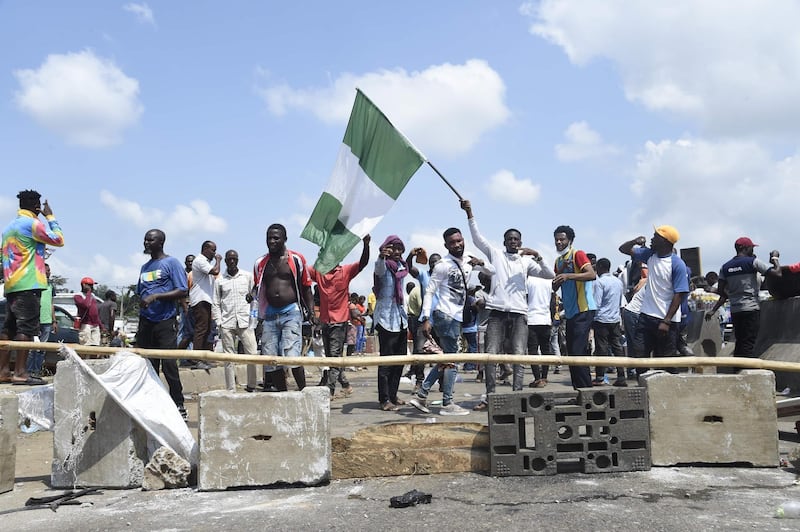 protester raise the Nigerian national flag at a barricade mounted by potesters on the Lagos-Ibadan expressway. AFP