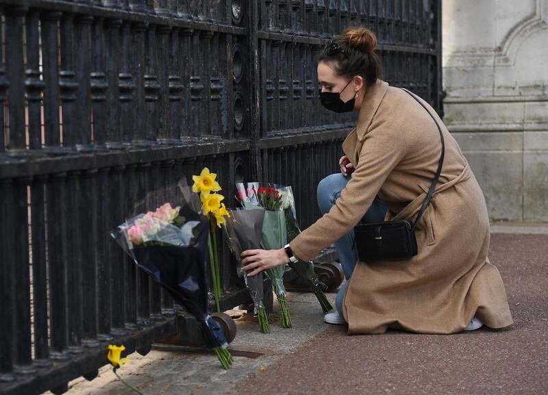 People place flowers and condolence messages outside Buckingham Palace following the death of Prince Philip. EPA