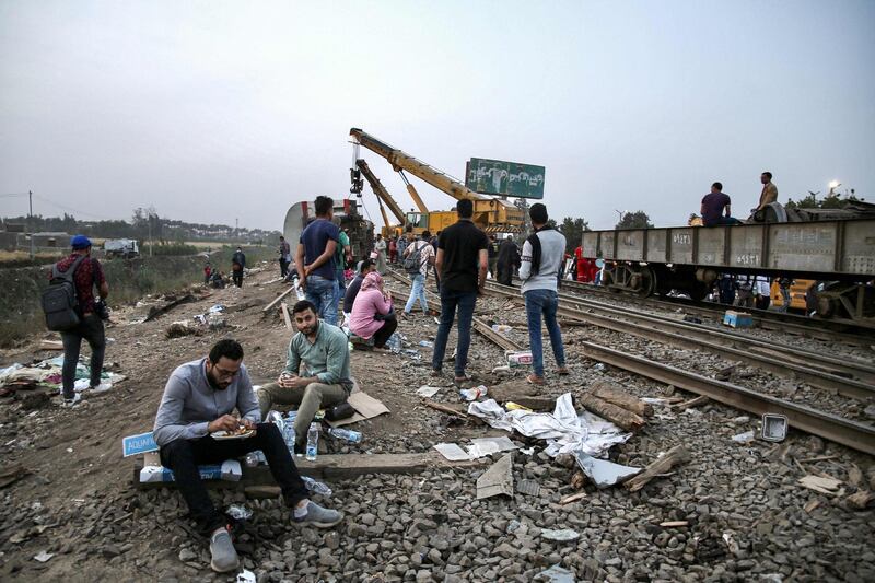 People break their fast as a crane lifts an overturned passenger coach at the scene of a railway accident near Banha, the capital of Qalyubia province, Egypt. AFP