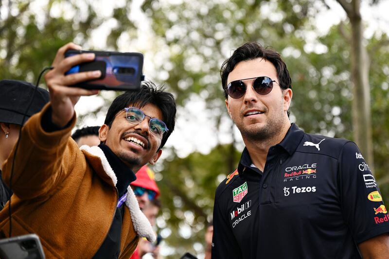 Red Bull driver Sergio Perez arrives at the circuit and poses for a photo with a fan. Getty