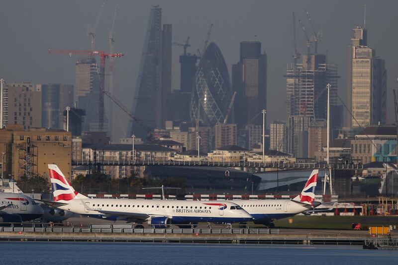(FILES) In this file photograph taken on October 27, 2017, British Airways aircraft taxi on the runway with the financial towers and office buildings of the City of London in the background before taking off from London City Airport in east London. IAG, owner of British Airways and other European airlines, posted on May 7, 2021, a net loss of 1.1 billion euros ($1.3 billion) in the first quarter as the coronavirus pandemic grounded planes. It was a reduction, however, on the company's net loss of 1.68 billion euros in the first three months of 2020 as Covid took off.

 / AFP / Daniel LEAL-OLIVAS
