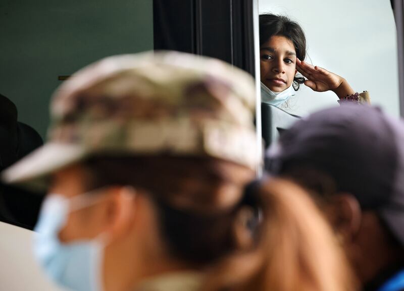 A young Afghan refugee salutes a member of the US Army as she waits on a bus after arriving at Dulles International Airport in Dulles, Virginia. Reuters