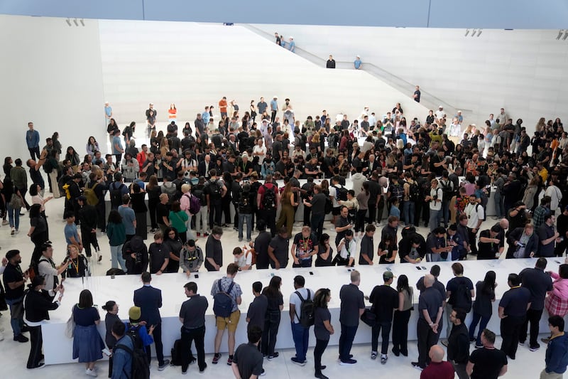 People gather around tables showing the new products on the Apple campus. AP