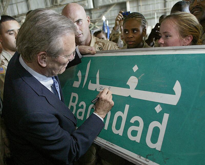 Donald Rumsfeld signs a road sign at the request of a US soldier in 2003, during a visit to troops at Baghdad's international airport. Reuters