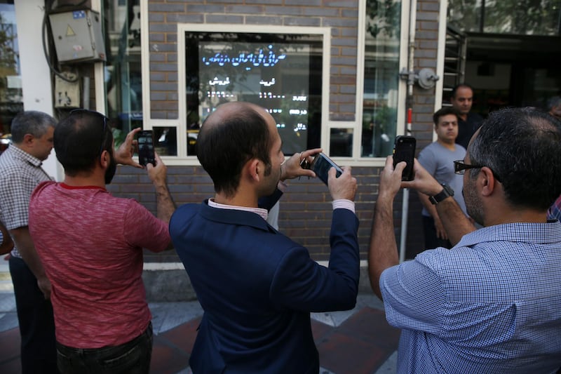 Iranians take pictures of an exchange shop screen showing various currency rates in downtown Tehran, Iran, Tuesday, Oct. 2, 2018. Iran's currency, the rial, unexpectedly rallied Tuesday after weeks of depreciation following President Donald Trump's decision to withdraw America from Tehran's nuclear deal with world powers, sending Iranians rushing to exchange shops to cash in. (AP Photo/Vahid Salemi)