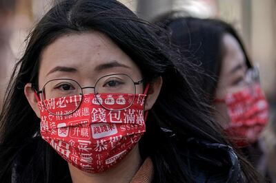 Women wearing face masks printed with various fortune words tour the Nanluoguxiang, the capital city's popular tourist spot on the fifth day of the Lunar Chinese New Year in Beijing, Tuesday, Feb. 16, 2021. (AP Photo/Andy Wong)