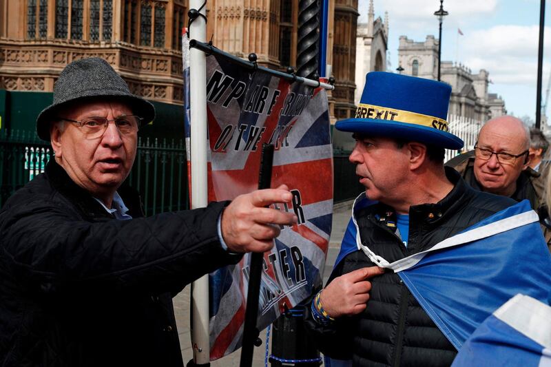 Anti-Brexit campaigner Steve Bray (2nd R) and a pro-Brexit supporter clash outside the Houses of Parliament in London on March 25, 2019. Accused of presiding over an unprecedented national humiliation in her chaotic handling of Brexit, British Prime Minister Theresa May has all but lost control of her party and her government. / AFP / Adrian DENNIS
