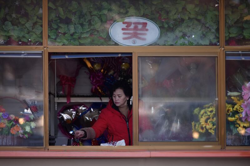 A flower vendor waits to hand out flowers to people arriving to pay their respects. AFP