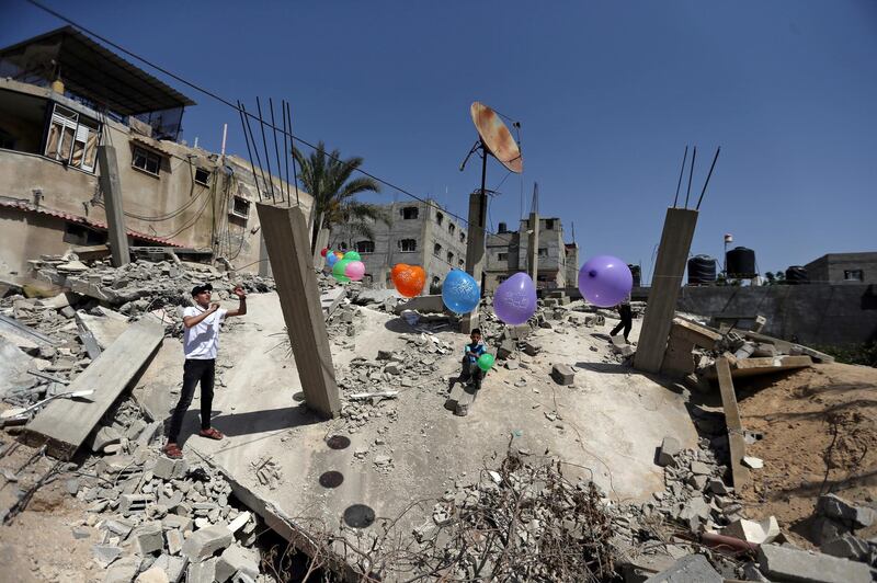 A Palestinian man hangs balloons over the ruins of a house that was destroyed in recent Israeli air strikes, ahead of the Muslim holiday of Eid Al Fitr in Rafah in the southern Gaza Strip. Reuters