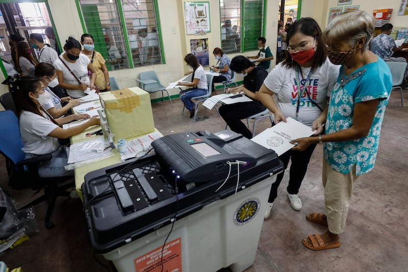 People feed their ballots into a vote-counting machine at a centre in Cainta town. EPA