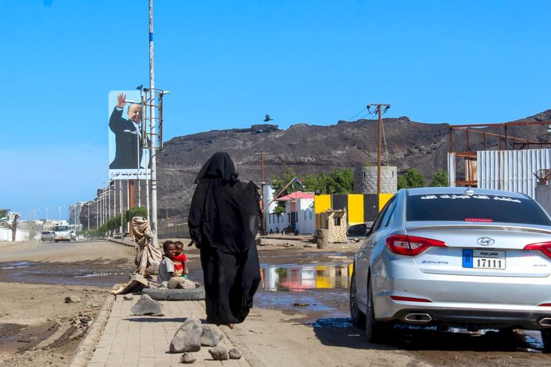 A woman begs for money, next to her children, from a vehicle in the southern Yemeni city of Aden on April 27, 2020, during the Muslim holy month of Ramadan.  / AFP / Saleh Al-OBEIDI
