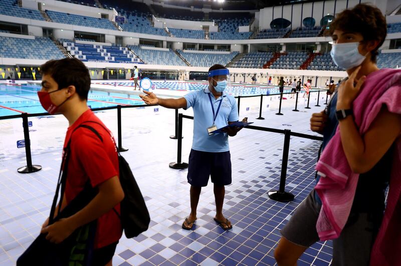 A staff member directs swimmers to the correct swimming zone at Hamdan Sports Complex. Pools have reopened in Dubai Getty Images