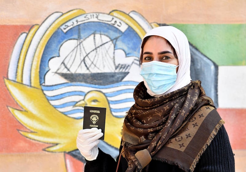 A Kuwaiti woman wearing a protective masks waits to cast her votes at a polling station in Kuwait City. EPA