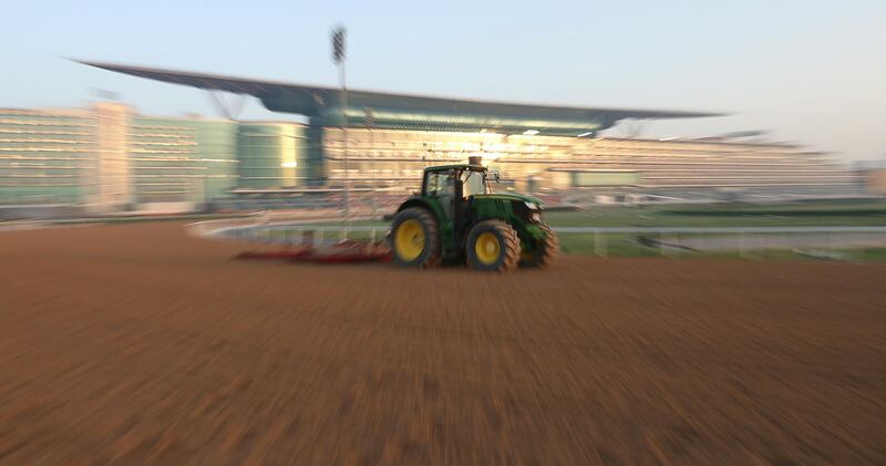 A tractor pulls a grooming machine during preparations for the Dubai World Cup 2021 at Meydan. EPA