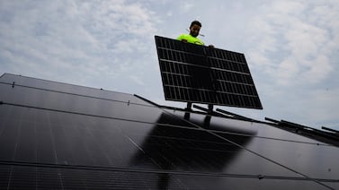 The US is galloping ahead of the UK in renewables. Nicholas Hartnett, owner of Pure Power Solar, holds a panel as his company installs a solar array on the roof of a US home. AP