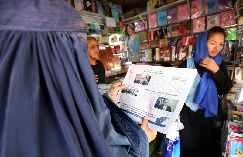 A woman reads a local newspaper displaying a photo of U.S. President Donald Trump on its front in Kabul, Afghanistan, Tuesday, Aug. 22, 2017. Reversing his past calls for a speedy exit, Trump recommitted the United States to the 16-year-old war in Afghanistan Monday night, declaring U.S. troops must "fight to win." (AP Photo/Rahmat Gul)