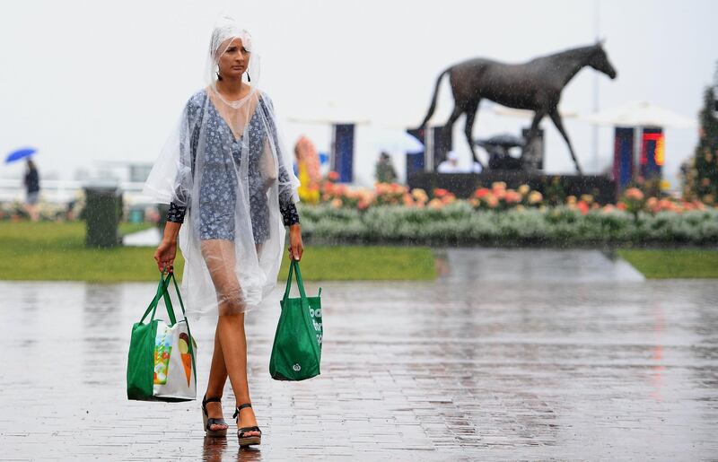 A woman wearing a raincoat and carrying shopping bags arrives for the annual Melbourne Cup, the world's richest two-mile handicap, at Flemington Racecourse in Melbourne, Australia. AFP